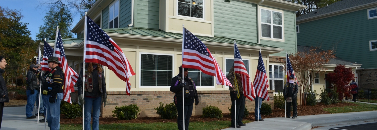 veterans outside a home with american flags for an open house ceremony